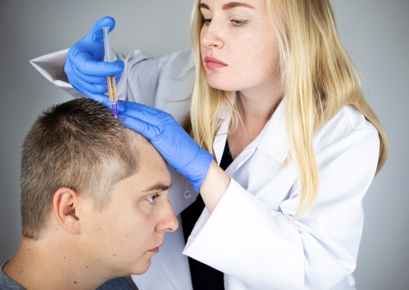 Trattamento della caduta dei capelli, un medico inietta un farmaco nella testa di un signore, un paziente