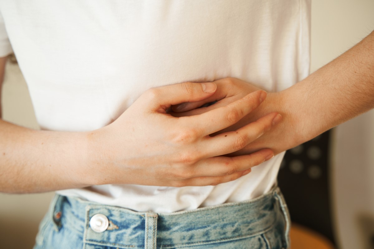 La donna si tiene il fianco dolorante con le mani, ha dolori addominali e altri problemi di salute che possono indicare un'ostruzione intestinale.