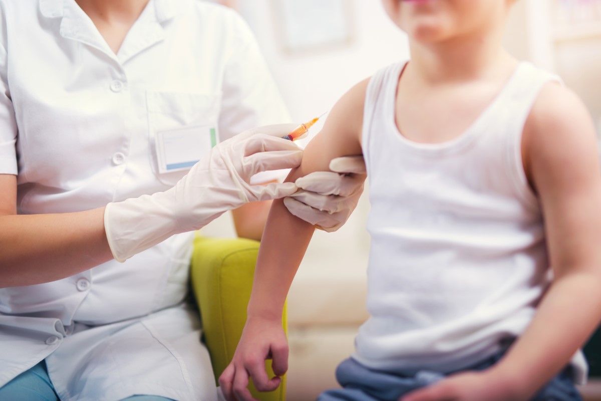 Vaccinare un bambino - il medico vaccina il bambino - il bambino si siede e il medico gli fa un'iniezione nel braccio.