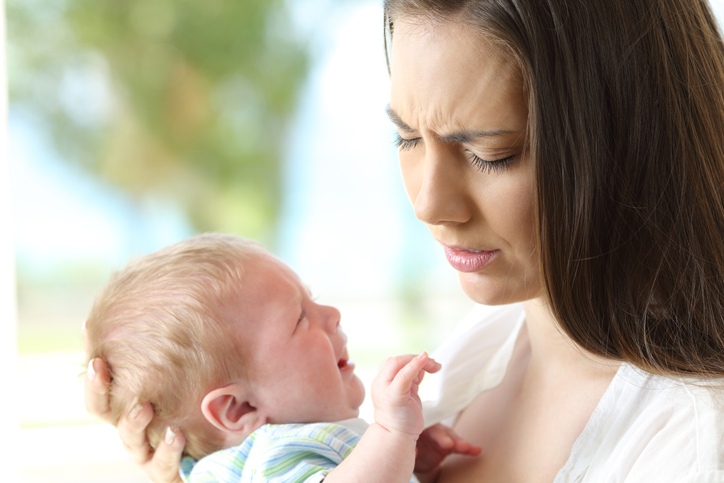 Un bambino che piange è tenuto in braccio dalla madre