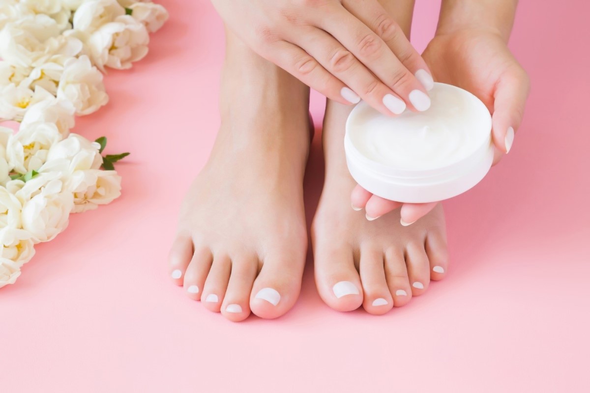 Applicazione della crema per i piedi Una donna si mette la crema sui piedi con le mani.