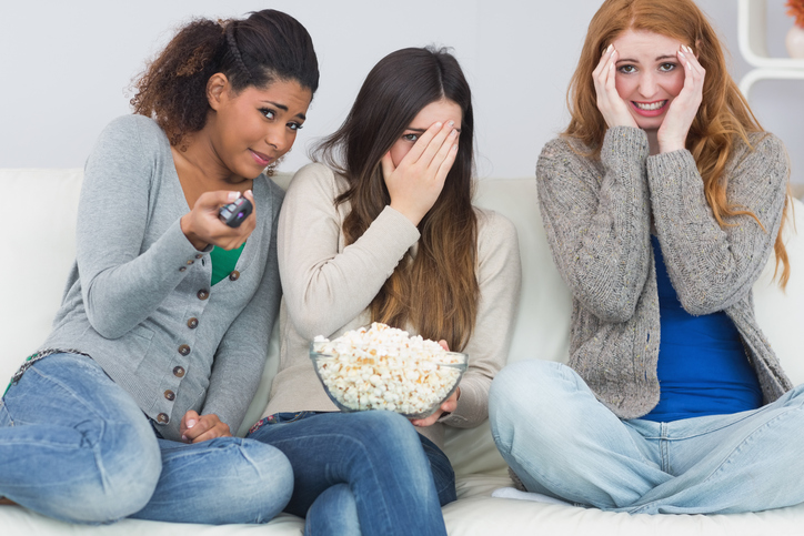 Tre ragazze sono spaventate, guardano un film di paura, popcorn in una ciotola