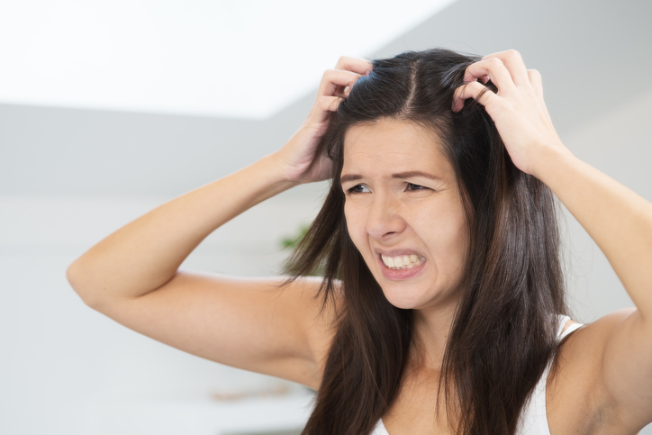 Una donna ha un problema di capelli, forfora, prurito al cuoio capelluto, si gratta la testa con le mani