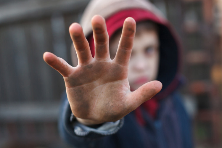 Bambino con le mani sporche e la mano rivolta verso di lui