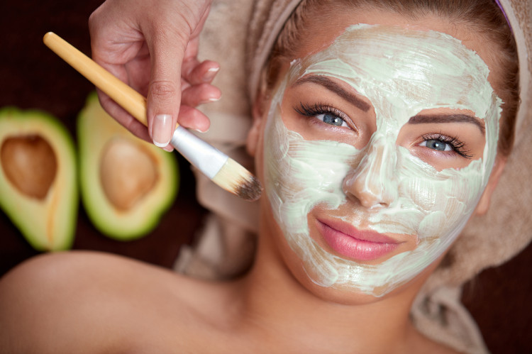 donna con un turbante in testa e una maschera naturale verde sul viso, sullo sfondo un avocado tagliato