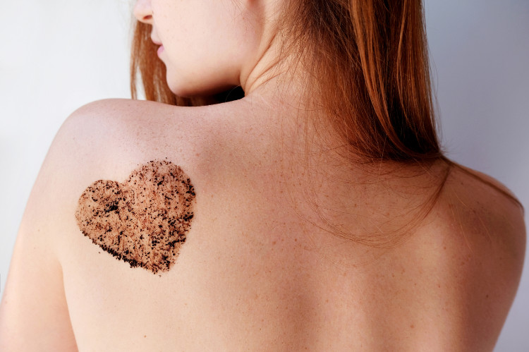 schiena di donna con un peeling marrone a forma di cuore sulla scapola sinistra