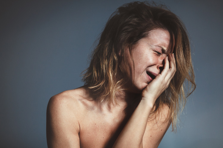 una donna in preda a una crisi di pianto si tiene il viso con la mano