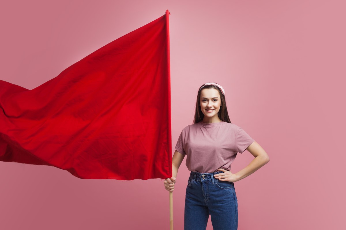 Una donna tiene in mano una grande bandiera rossa come avvertimento.