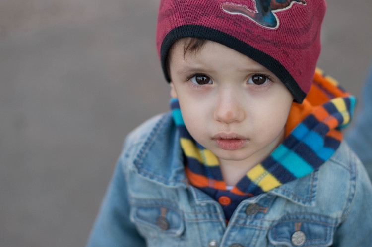 un bambino con una giacca blu e un berretto rosso che guarda nell'obiettivo