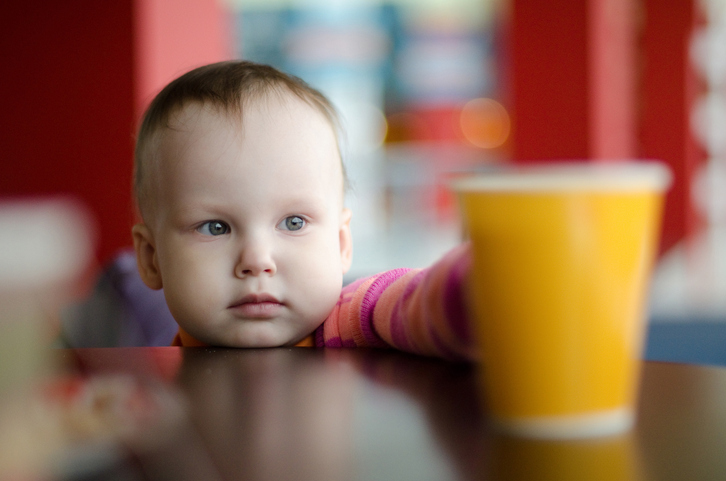 Un bambino piccolo prende un bicchiere d'acqua sul tavolo