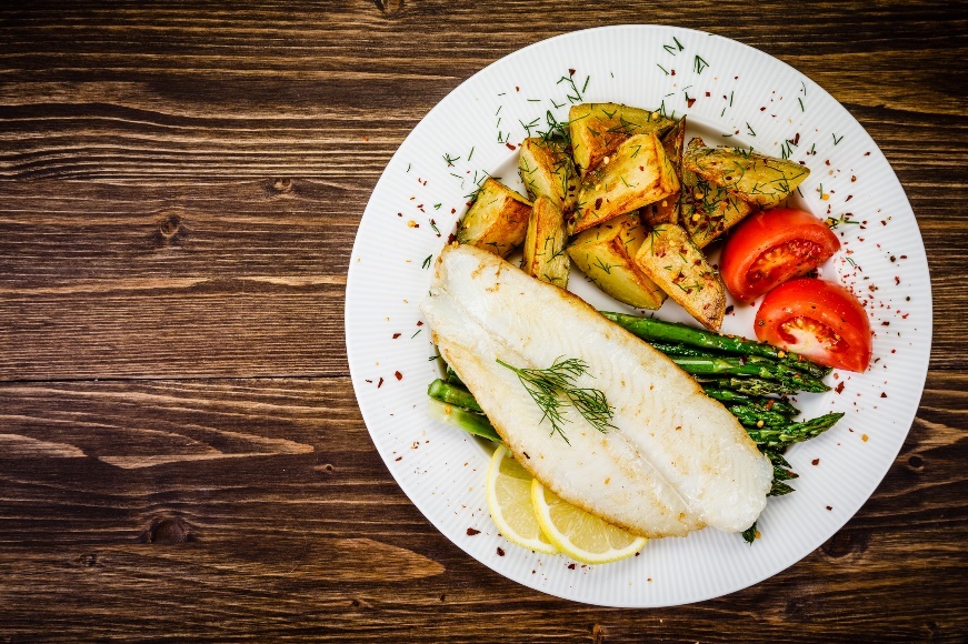 Esempio di cena: pesce alla griglia con asparagi, patate arrosto, erbe e verdure fresche.