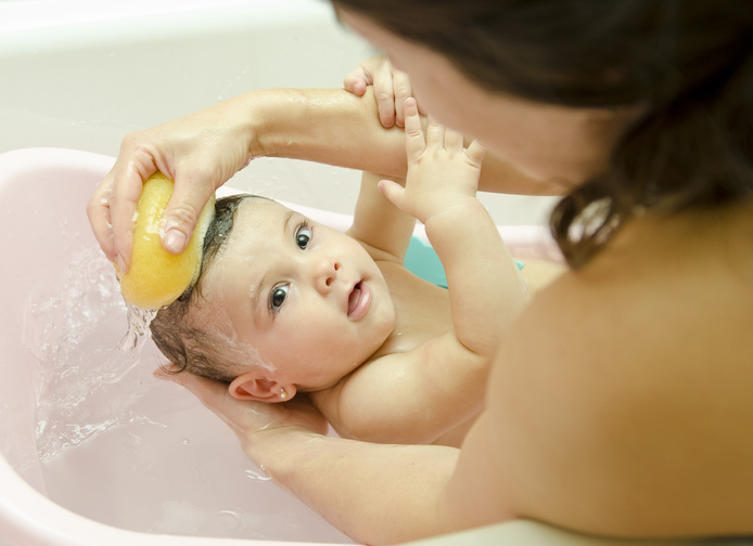 Madre che lava il suo bambino con una spugna