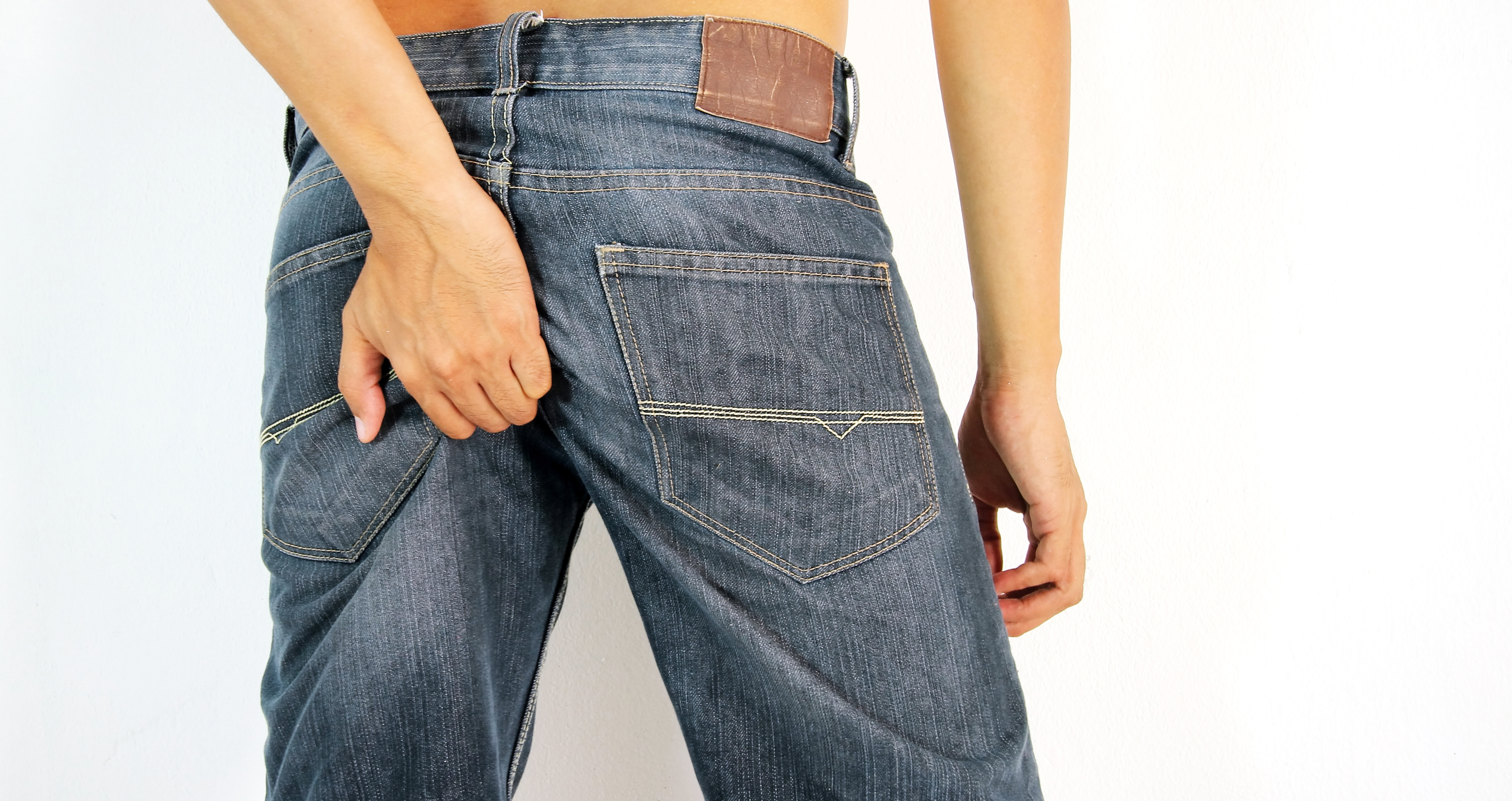 uomo in jeans che si gratta il culo