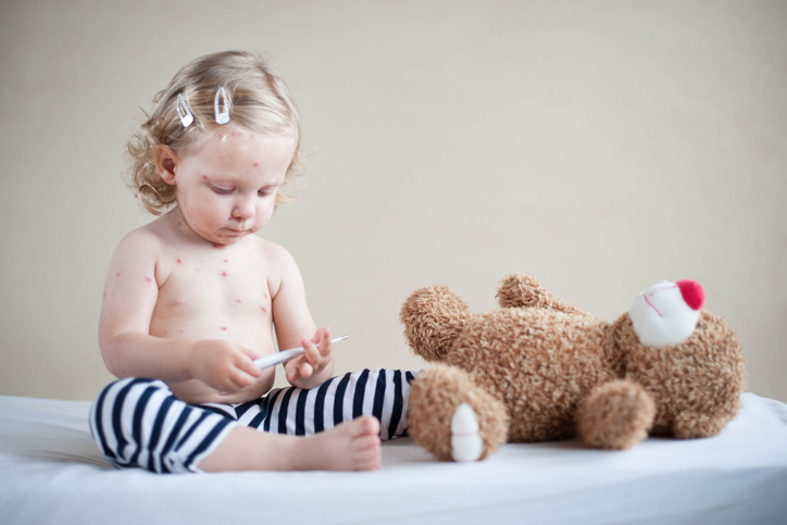 un bambino con il morbillo gioca con un orsacchiotto di peluche