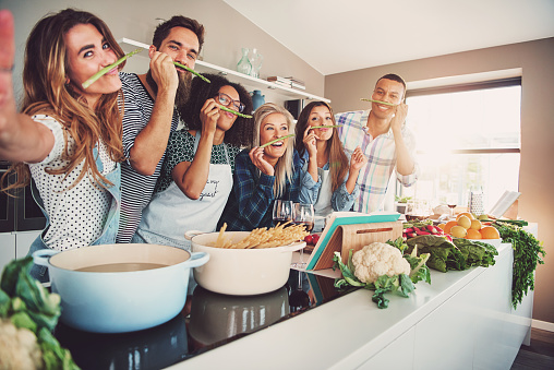 Persone che sorridono mentre preparano il cibo, dietro i fornelli.