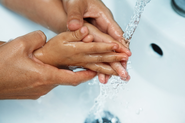 le mani della madre sul lavandino lavare le mani del bambino sotto l'acqua corrente