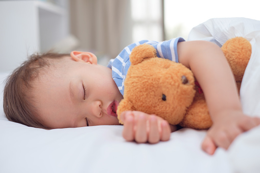 Bambino che dorme con l'orsacchiotto