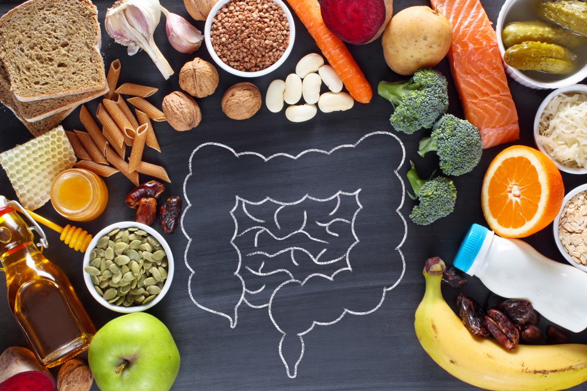 Vari alimenti, pasta, frutta, verdura, latticini, legumi e altro ancora, e l'intestino come esempio di connessione con la salute e i problemi del tratto digestivo.