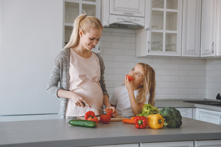 Madre e figlia incinta preparano un pasto sano in cucina.