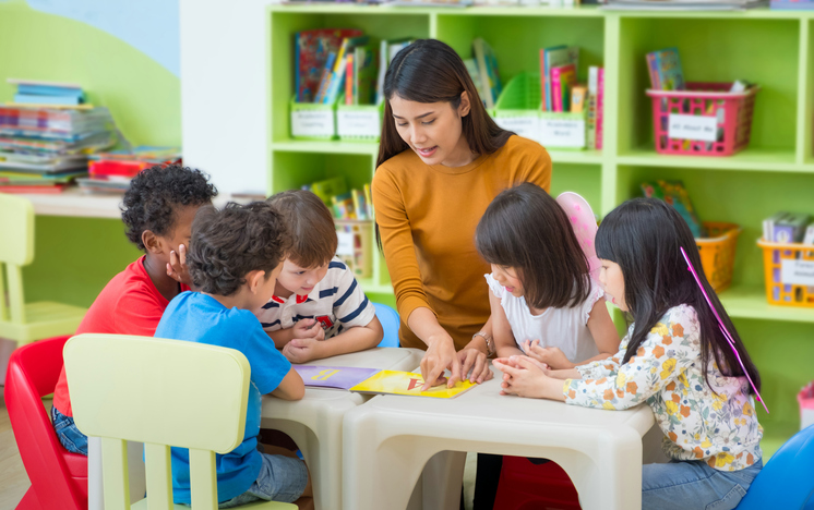 Una maestra d'asilo legge ai bambini un libro