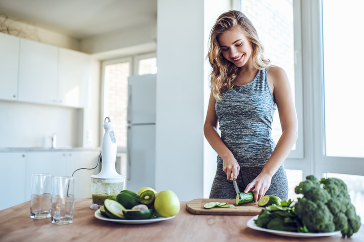 Una giovane donna taglia le verdure in cucina.