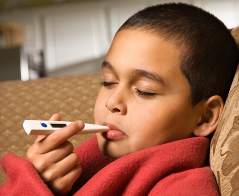 Il bambino misura la sua temperatura corporea con un termometro digitale in bocca.