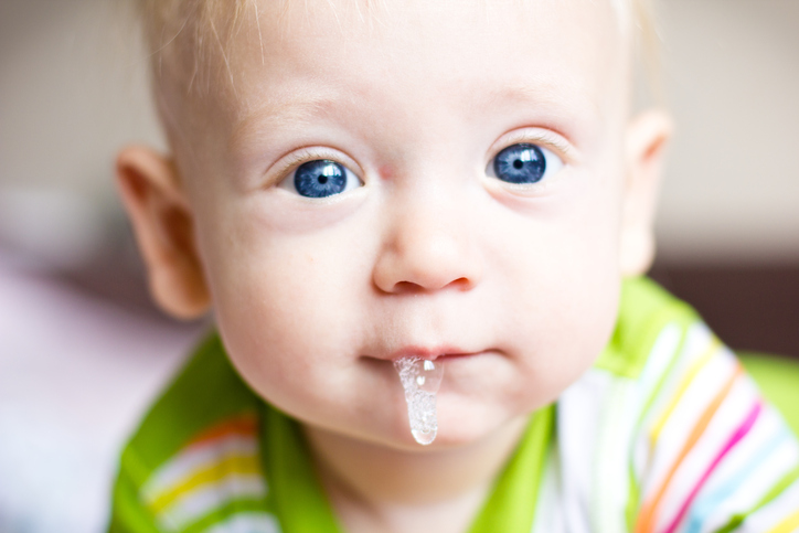 Un bambino piccolo, un neonato, sbava, gli cresce il primo dente