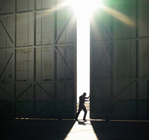 Un uomo esce dalla sala buia alla luce intensa, il sole splende, e apre una porta nella sala.