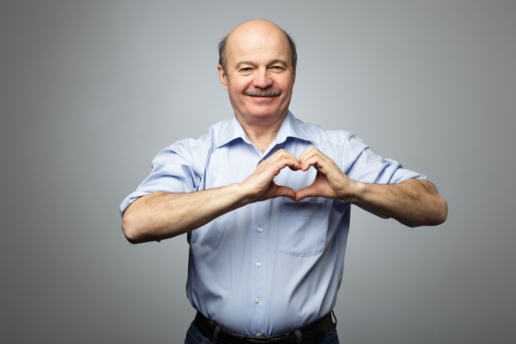 L'uomo più anziano ha le mani sul petto a forma di cuore, con un'espressione felice sul viso.