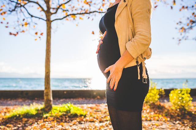 donna incinta in piedi davanti all'albero autunno