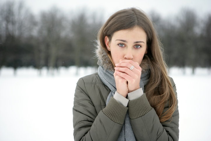 Una donna si scalda le membra fredde con il suo respiro, fuori nevica, freddo, freddo